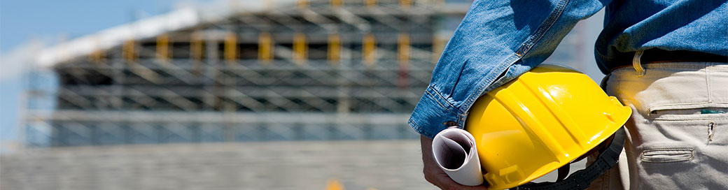 A professional construction worker holding his helmet and blueprint.