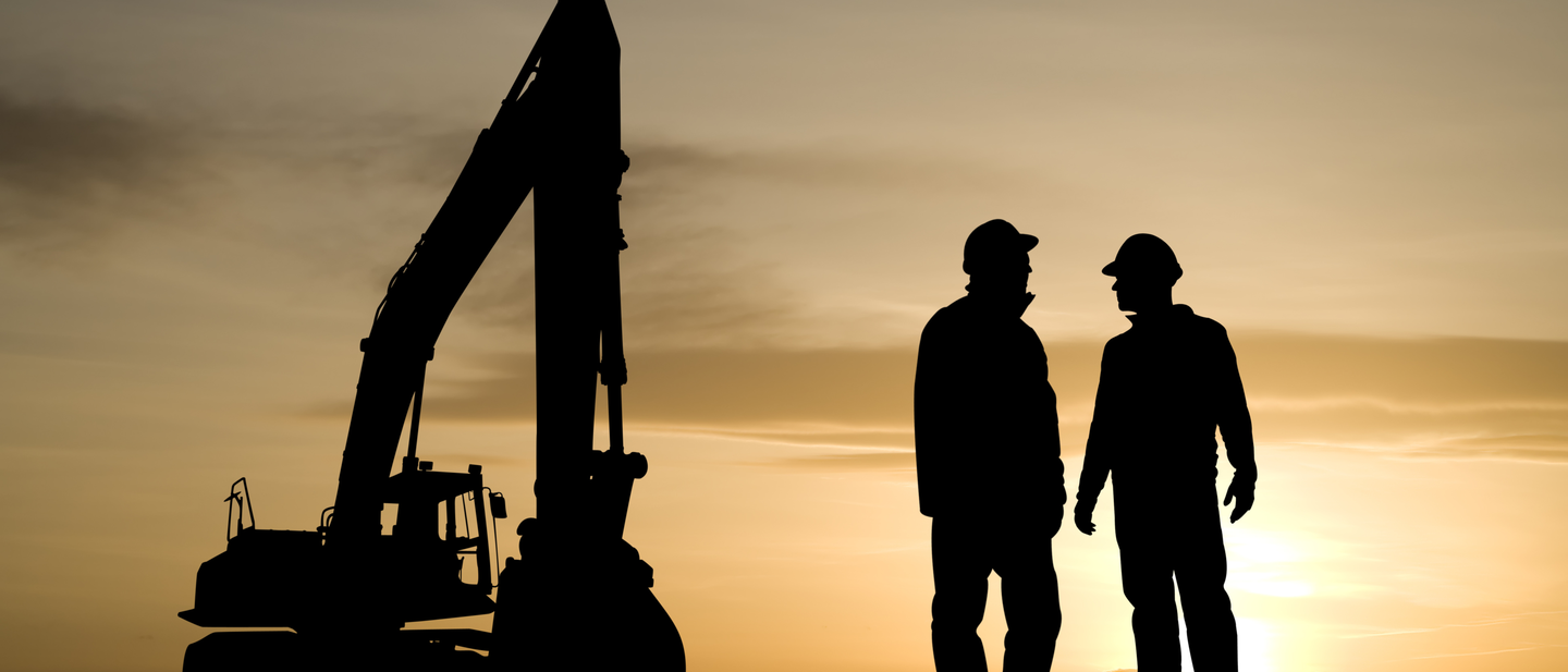 Two silhouetted construction workers and a construction shovel against a sunrise.