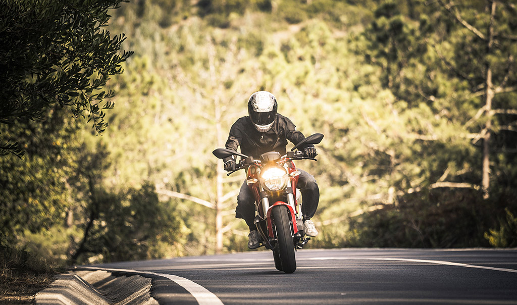 Person riding motorcycle down an empty road.