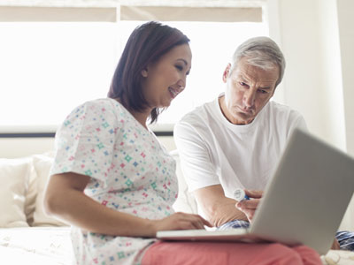 Woman in hospital uniform looking at laptop computer screen with man in white.