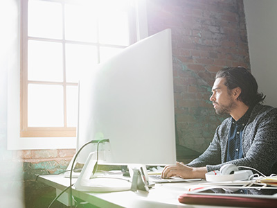 Man working at desk on desktop computer.