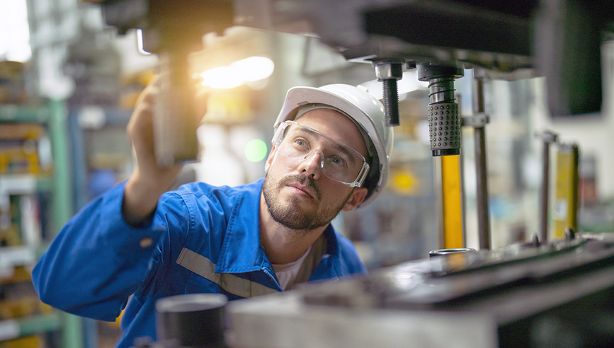 A man in safety equipment analyzing a machine for possible breakdown.