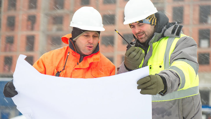 Two workers discuss a plan in cold weather.