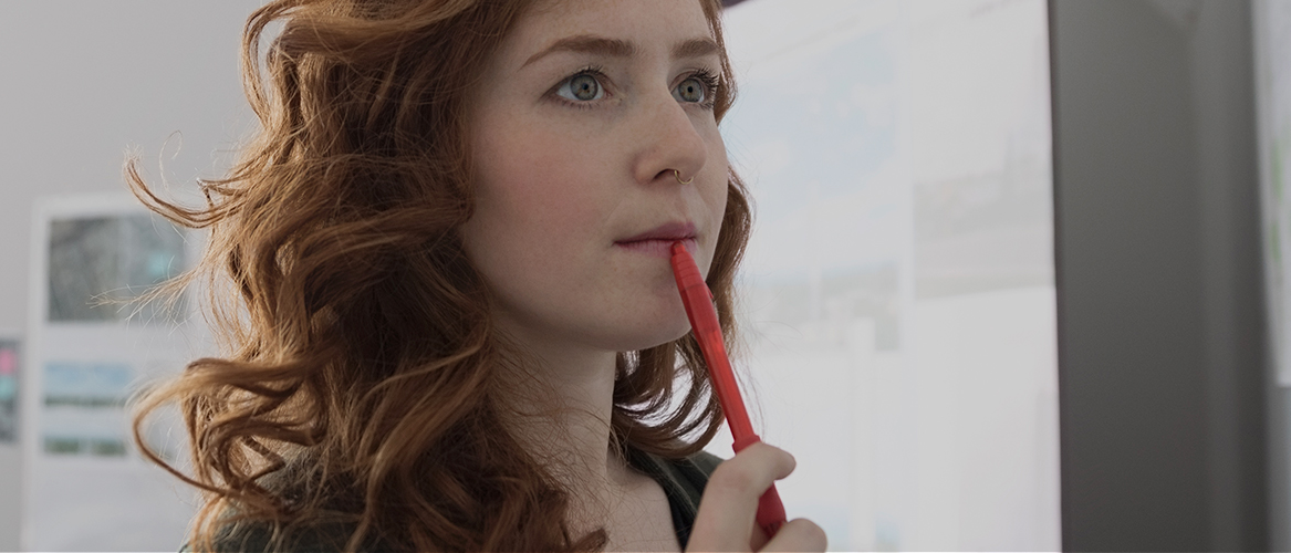 Woman thinking intently looking at a whiteboard.