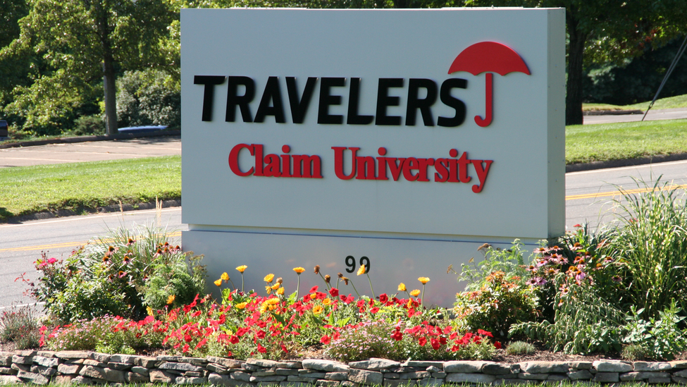 A Travelers Claim University sign sits neatly surrounded by flowers.