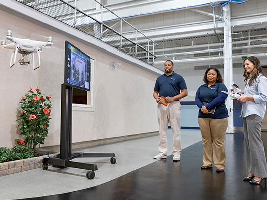 A male and two female co-workers watching electronic screen display.