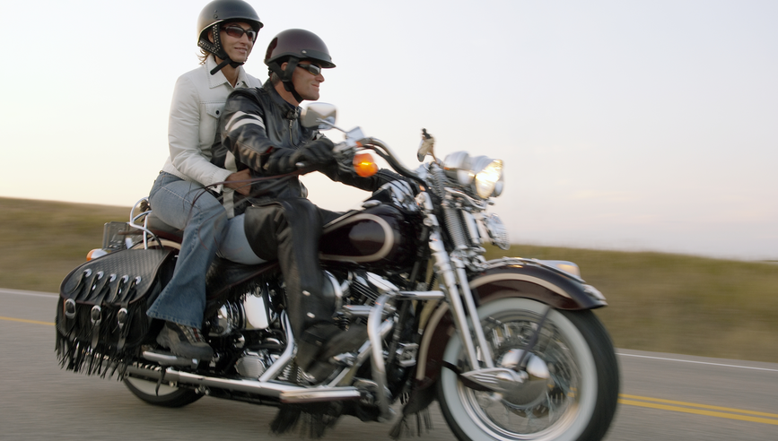 man and woman riding motorcycle wearing helmets