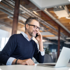 Man talking on phone while using laptop.