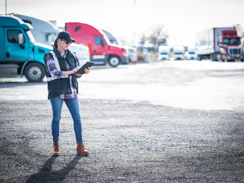woman looking at ipad in parking lot with trucks