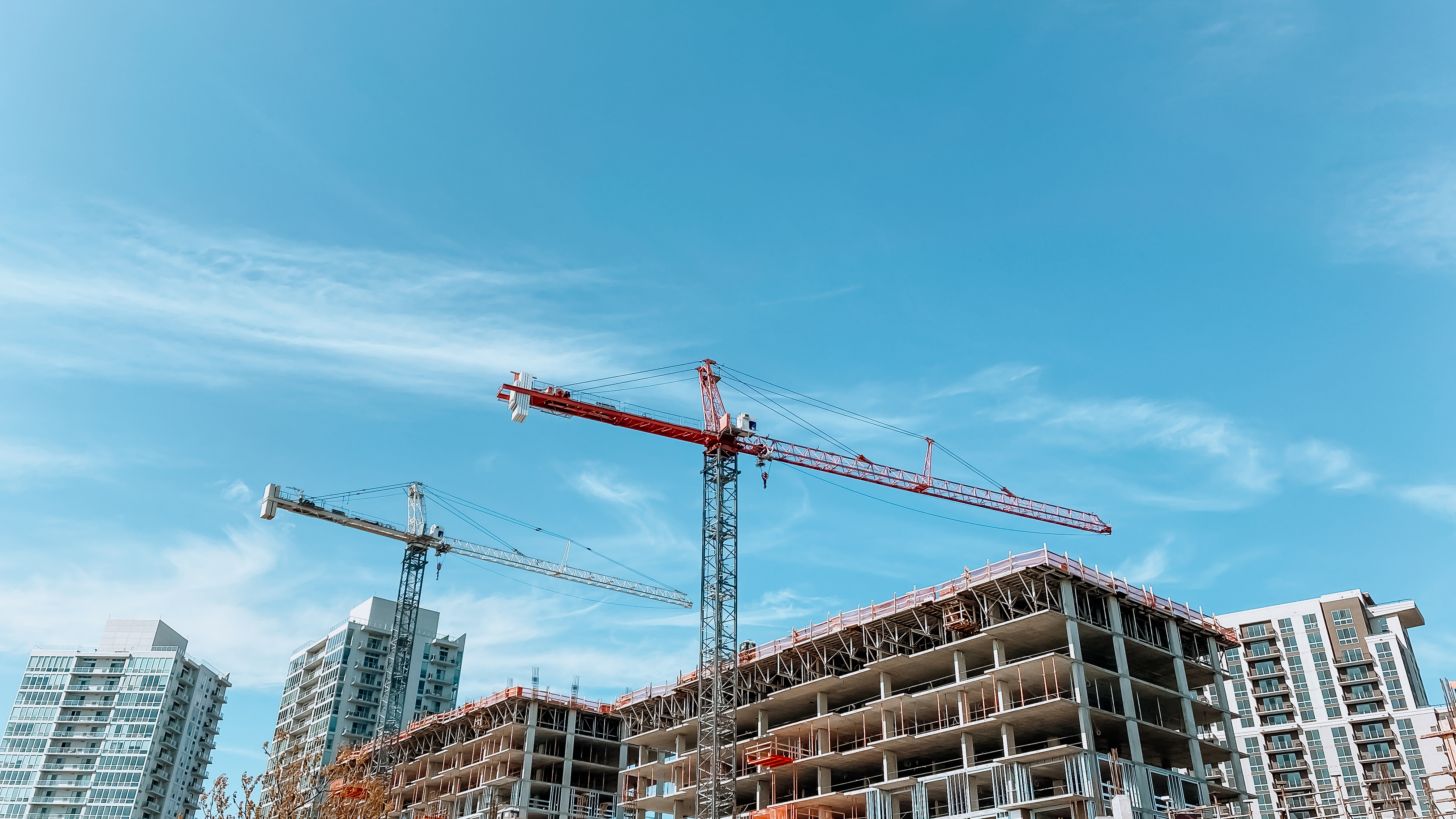 Two cranes high above a building under construction.