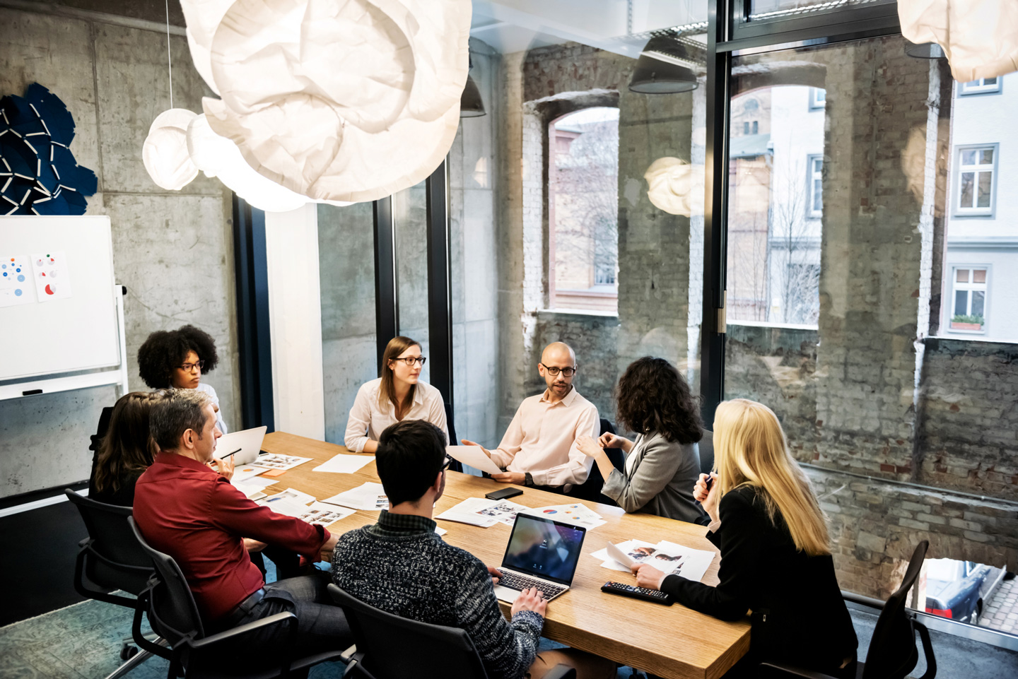 A group of business professionals engaged in discussion within a meeting room.