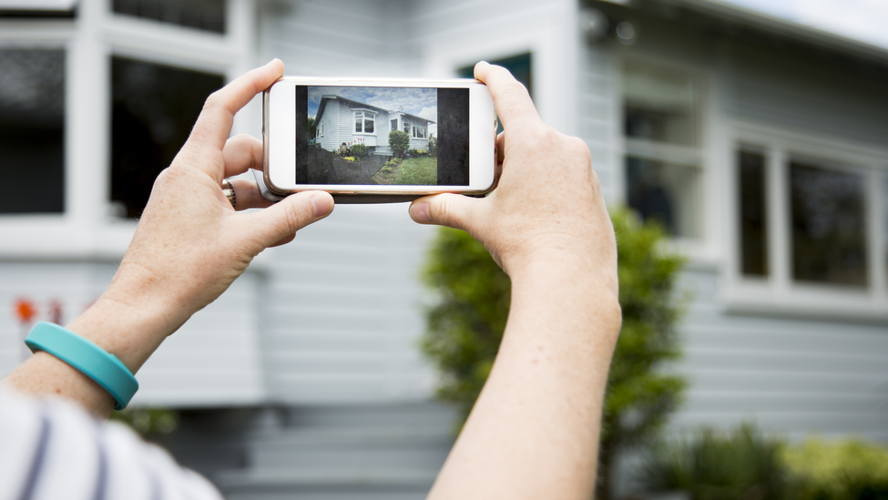 woman takes picture of house with smart phone.