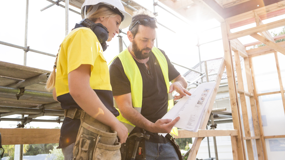 Male and female construction workers discuss the building plans inside the building site