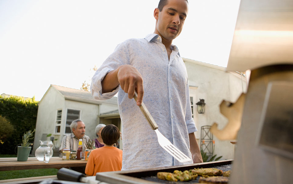 Person standing at a grill cooking food