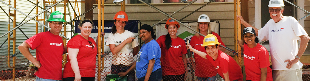 Travelers employees in front of house constructed for habitat for humanity.