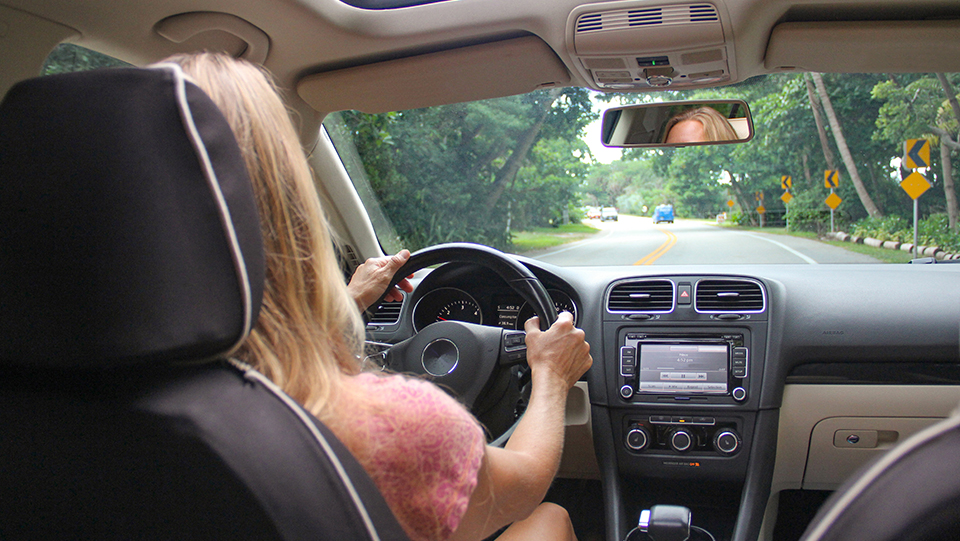 Image taken from back seat of a car of woman driving the car.