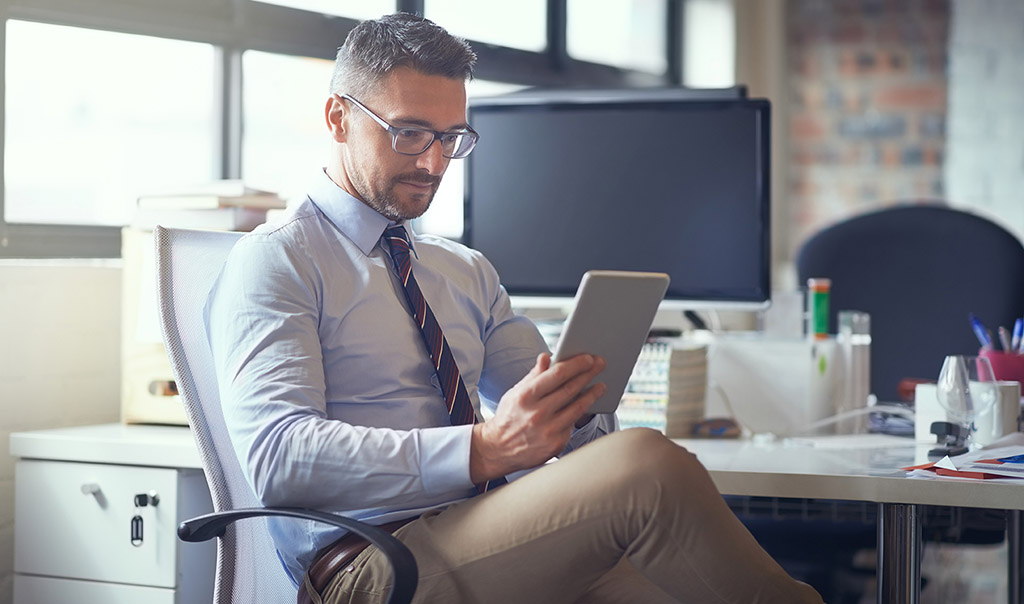 Businessman sitting at a desk holding a digital tablet