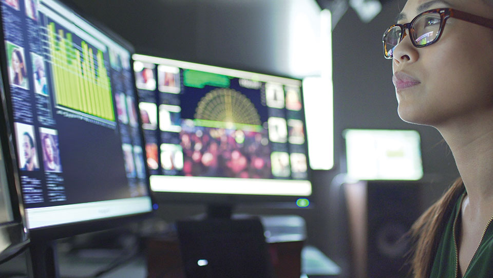 Woman in front of computer panels.