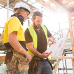 Male and female construction workers discuss the building plans inside the building site