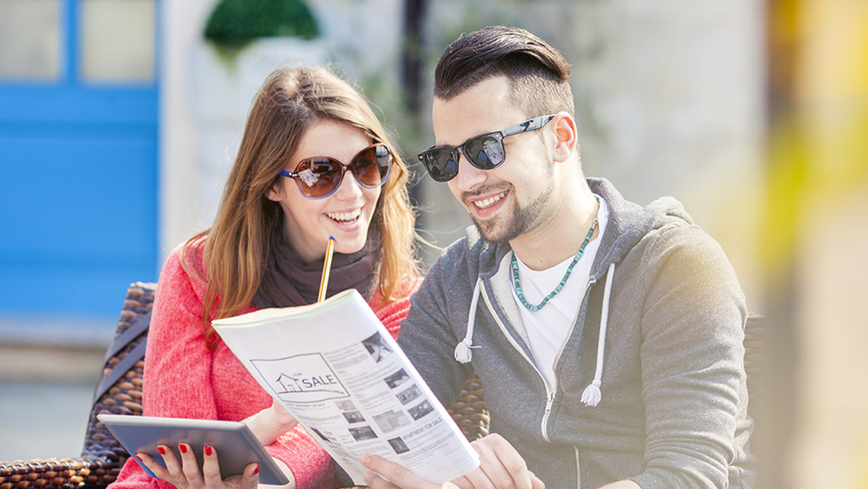 Man and woman smiling looking at home listing flyer.
