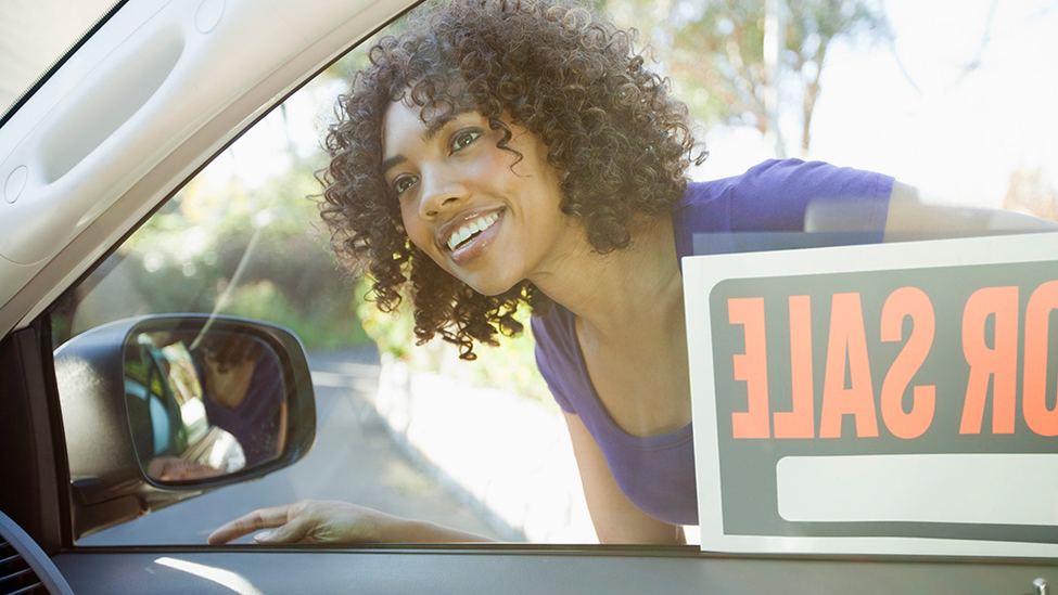 Woman looking in car window with.