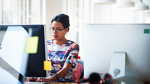 An employee is sitting at her desk working on a computer. 