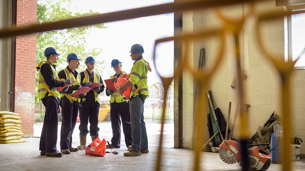 Construction workers analyzing risk while standing in a warehouse.