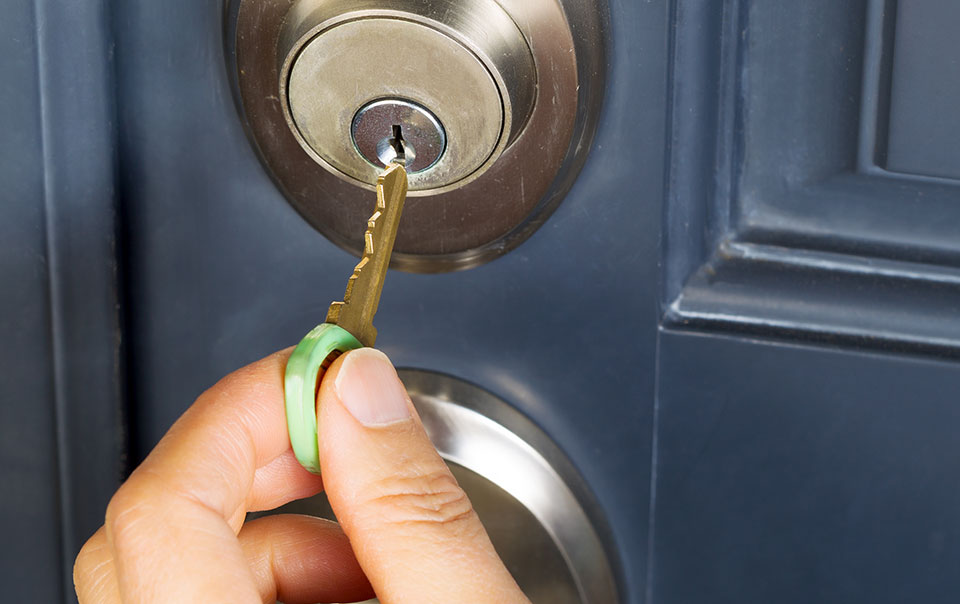 Person using a key to lock a deadbolt
