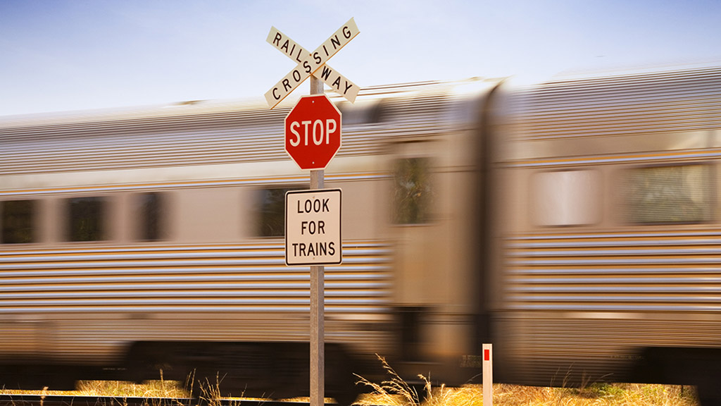 a train speeding past a railroad crossing sign