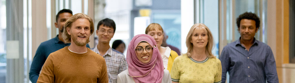 Group of people walking down a hallway.