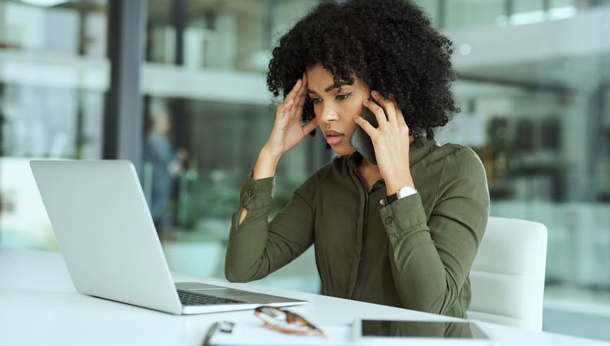 Young and frustrated African-American woman on the phone while researching on her laptop