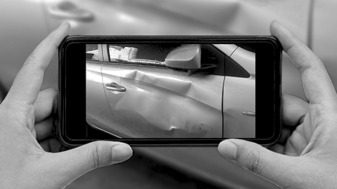 Person holding a smartphone to take photo of car after an accident.