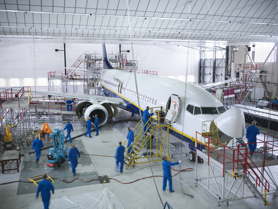 Workers service a large aeroplane in a hanger.