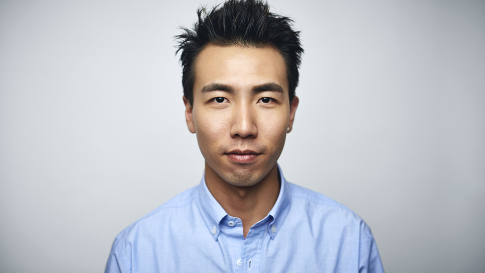 Portrait of young businessman. Male executive is wearing blue shirt. He is against white background.