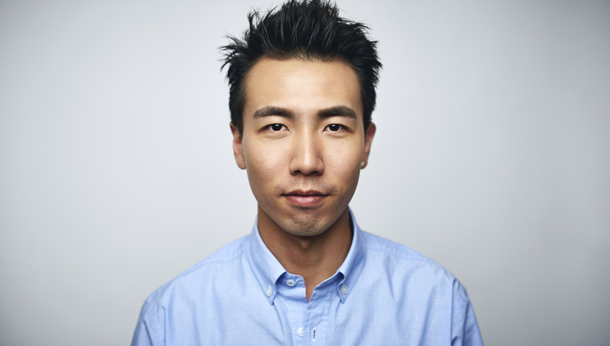 Portrait of young businessman. Male executive is wearing blue shirt. He is against white background.