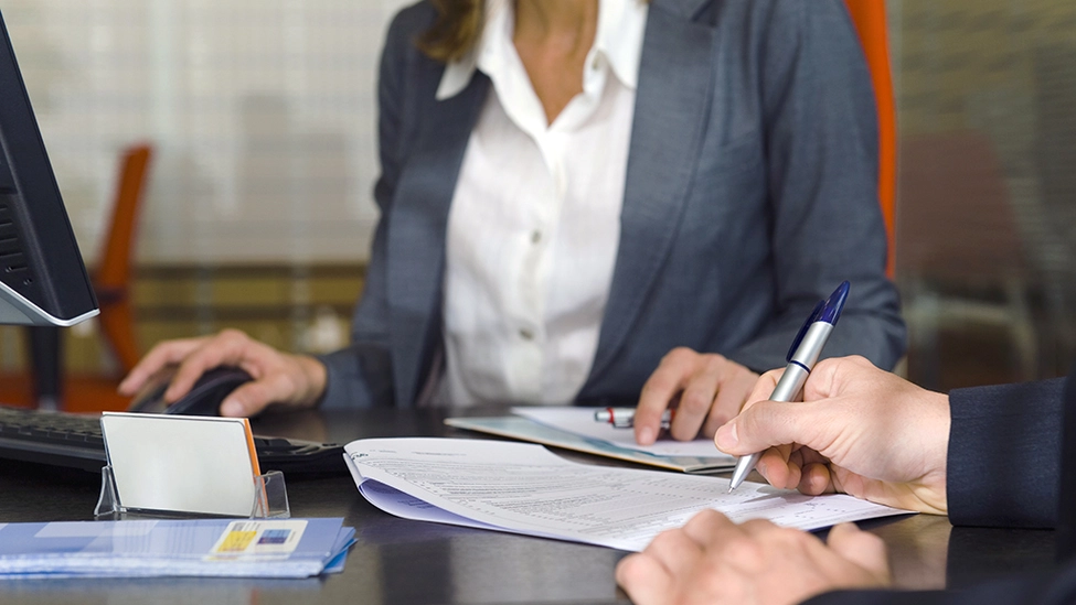 A woman and an individual are having a meeting to sign a contract.