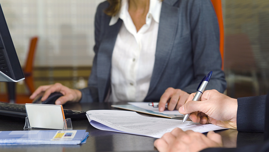 A woman and an individual are having a meeting to sign a contract.