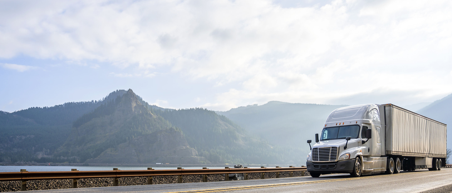 Goods being transported by semi-truck on a scenic highway.