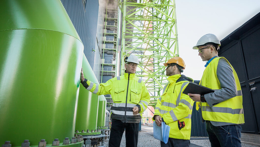 Three men talking at a powerplant.