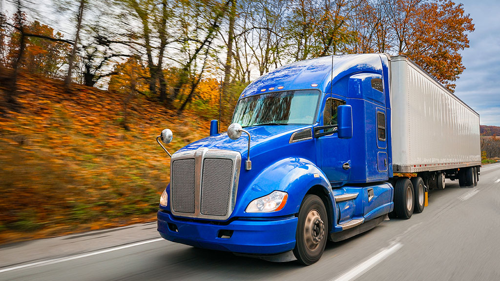 blue 18-wheeler truck driving down a road or highway