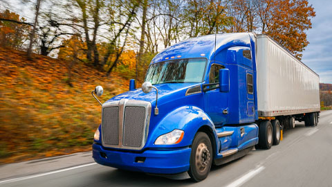 Blue 18-wheeler truck driving along highway