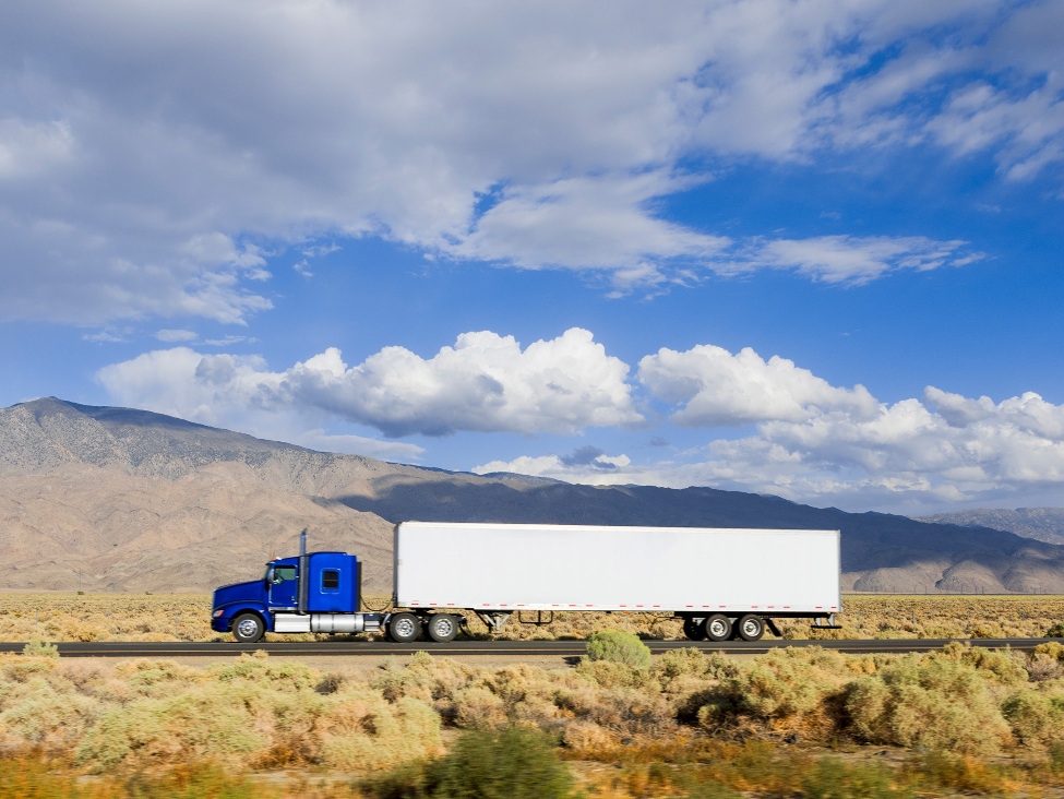 Blue and white truck driving on Highway 395 in Owens Valley.