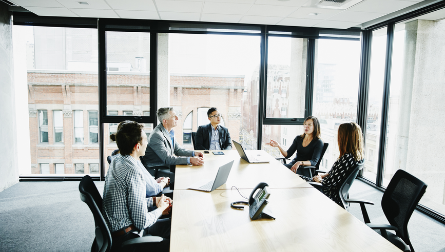 A group of business executives meet in a board room.