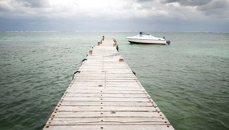 Boat on the water tied to the end of a dock.