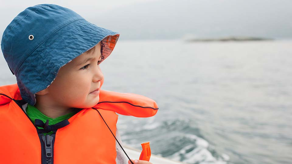 Small child on a boat wearing a lifejacket.