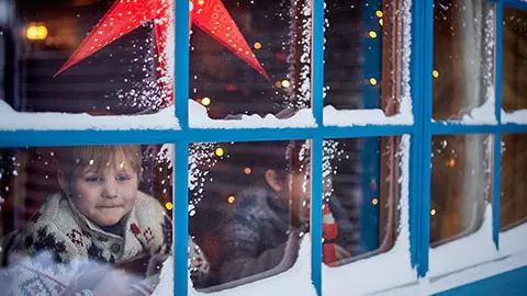 Boy looking out snowy window during the holiday.
