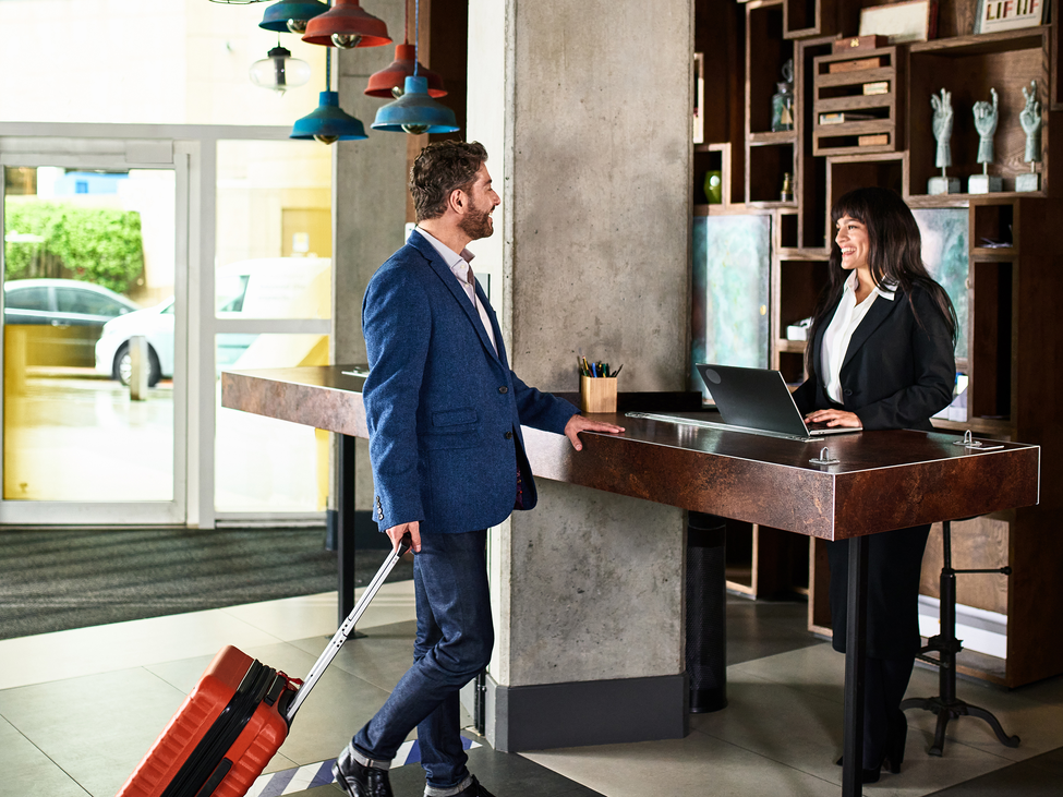 Holiday traveller checks in at a hospitality front desk.