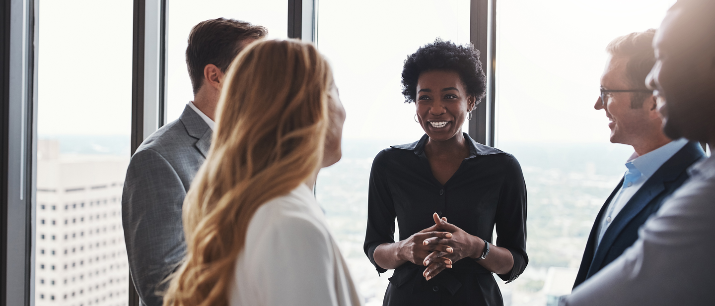 A group of office workers chat in a workspace.  