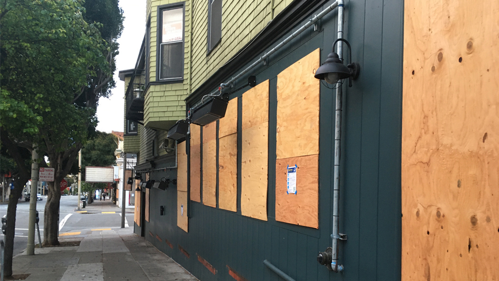 Street view of business windows boarded up to protect property.