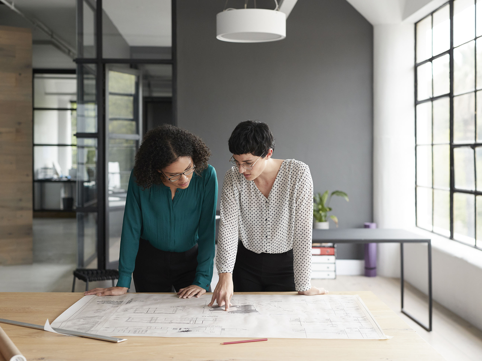 Two businesspeople look at plans for their small business office.